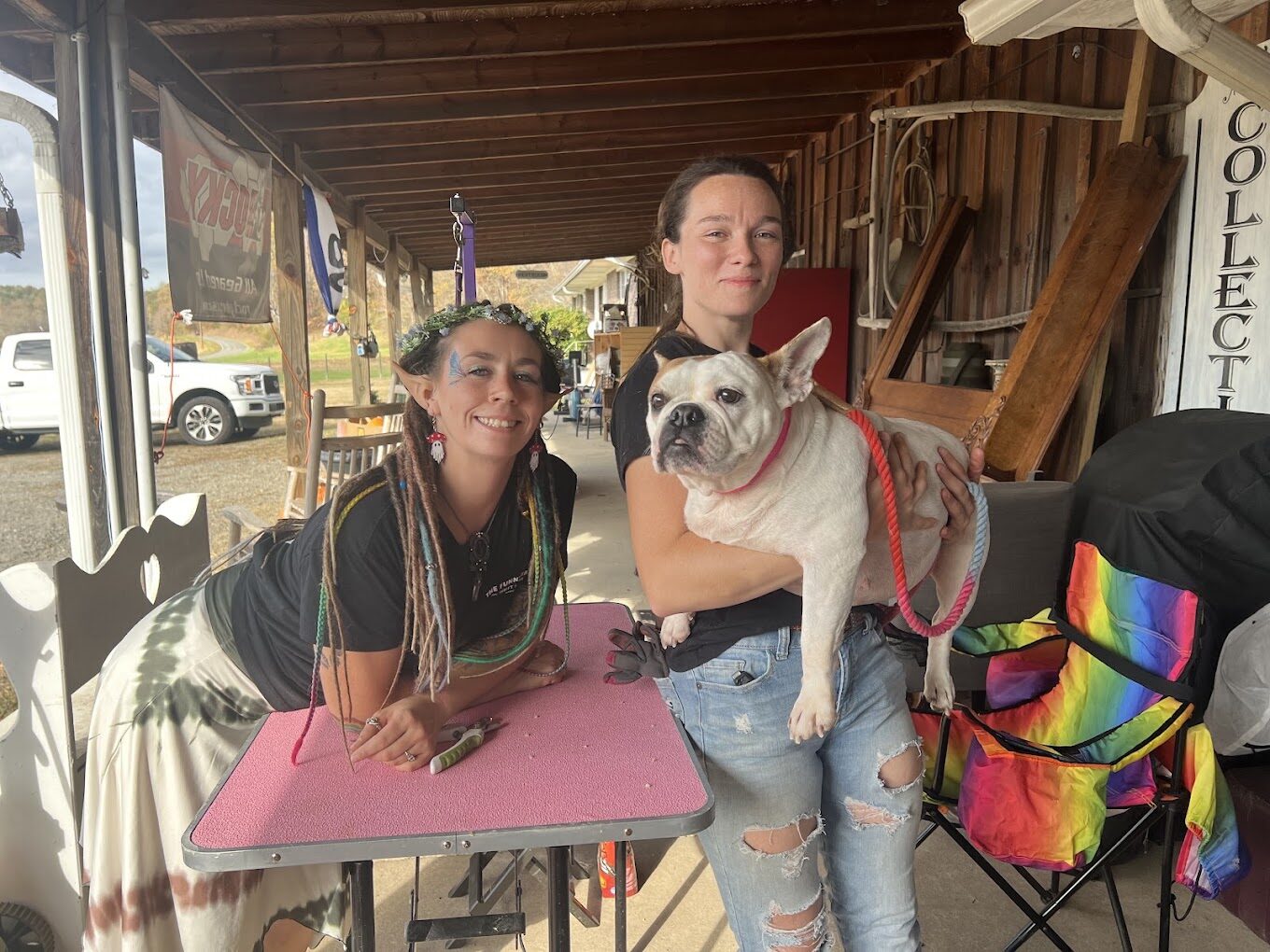 Volunteer holding a dog at the nail trim station on the porch